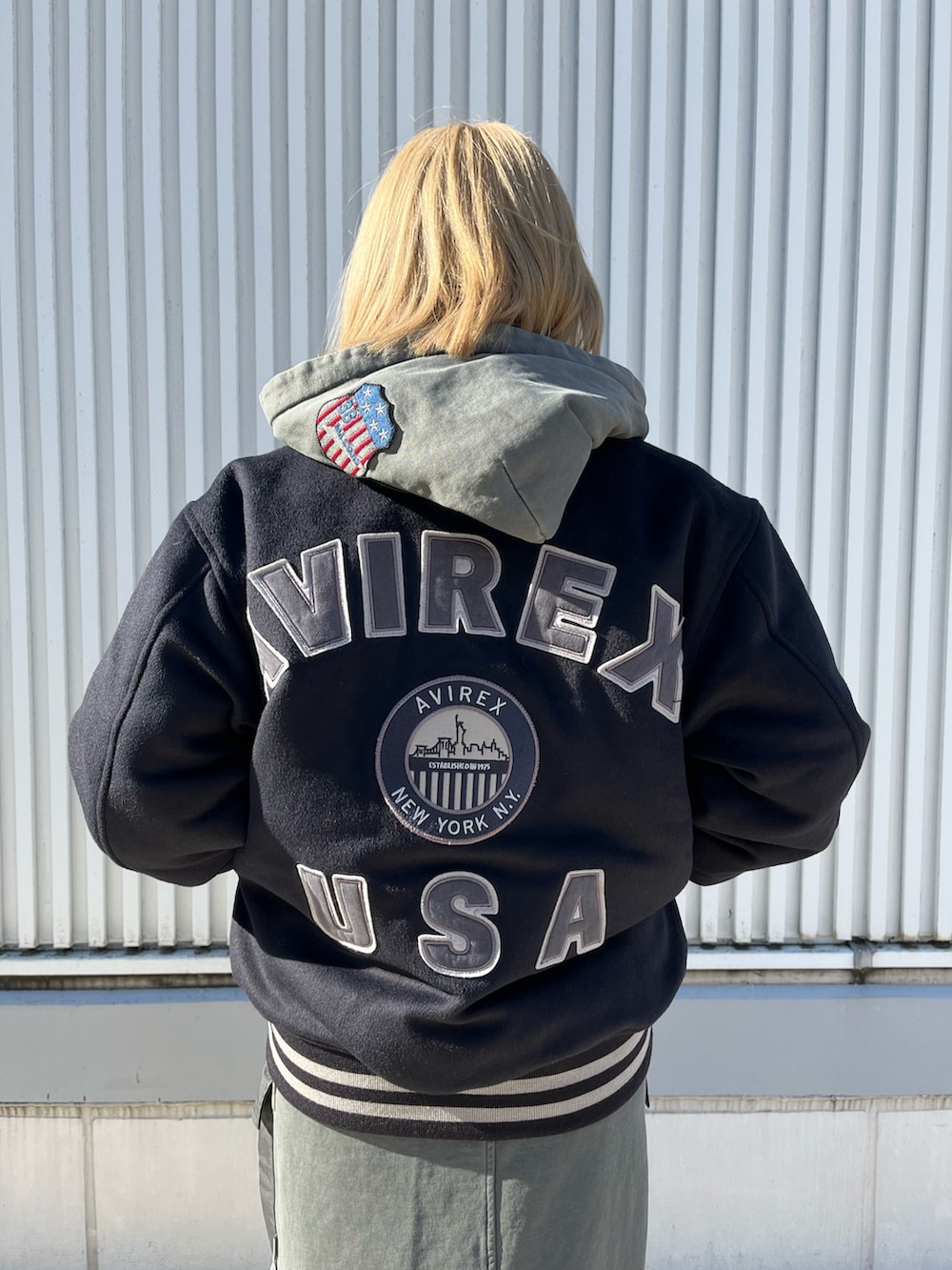 グレー系のパーカー、ブルー系のスタジャン、グレー系のスカートを着用したレディースの冬コーディネートの3枚目の写真