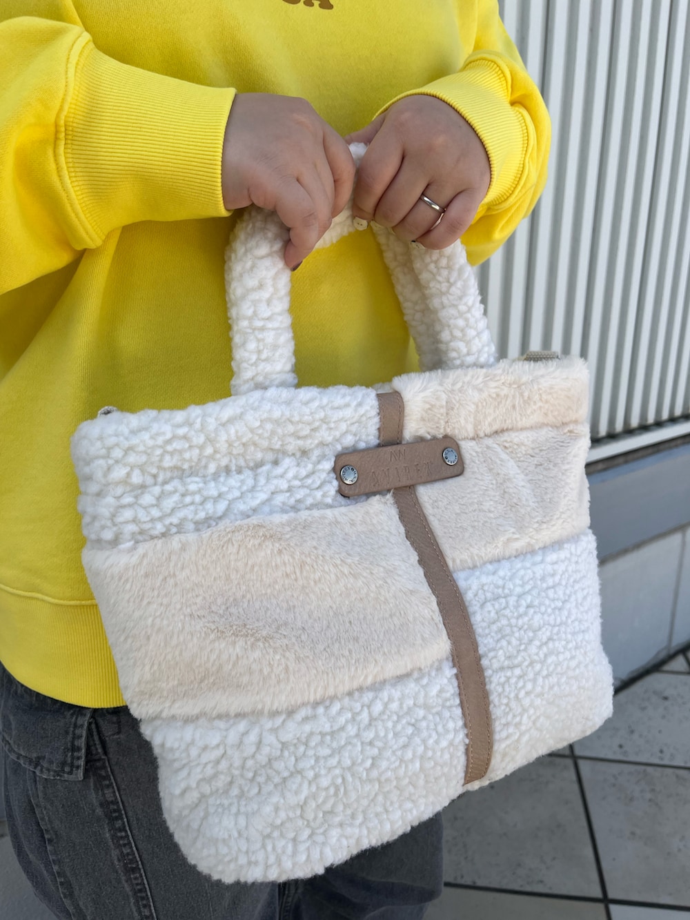 イエロー系のスウェット、ホワイト系のトートバッグ、ブラック系のデニムパンツを着用したレディースの秋コーディネートの5枚目の写真