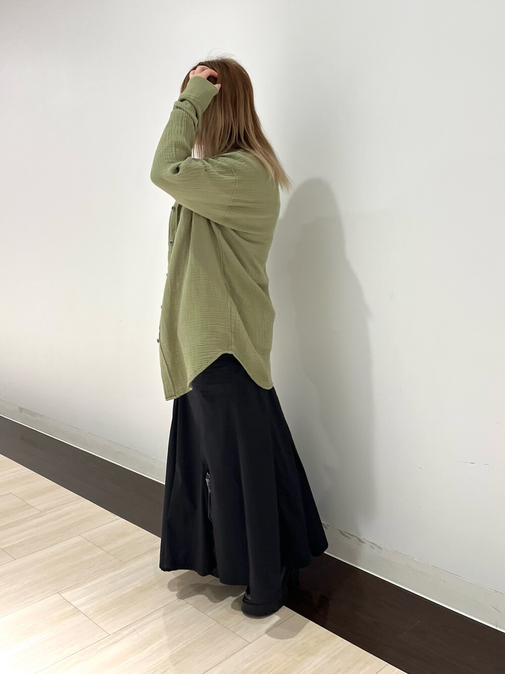 オレンジ系のシャツ/ブラウス、グリーン系のスカート、ベージュ系のTシャツ/カットソーを着用したレディースの春コーディネートの2枚目の写真