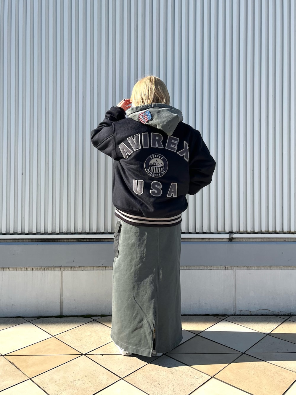 グレー系のパーカー、ブルー系のスタジャン、グレー系のスカートを着用したレディースの冬コーディネートの2枚目の写真