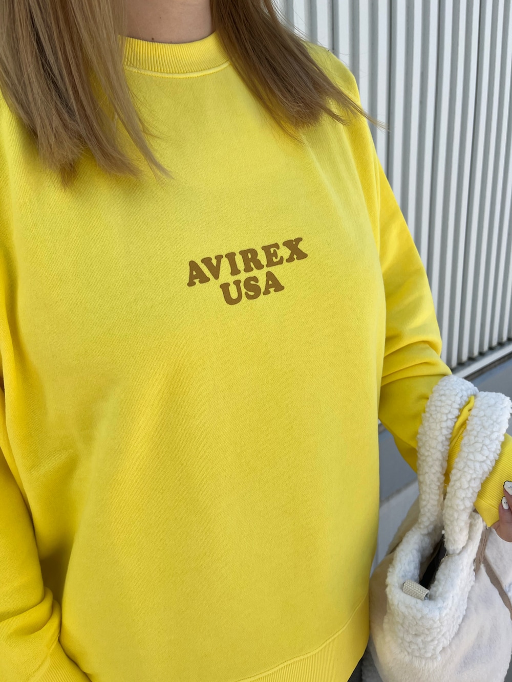 イエロー系のスウェット、ホワイト系のトートバッグ、ブラック系のデニムパンツを着用したレディースの秋コーディネートの4枚目の写真