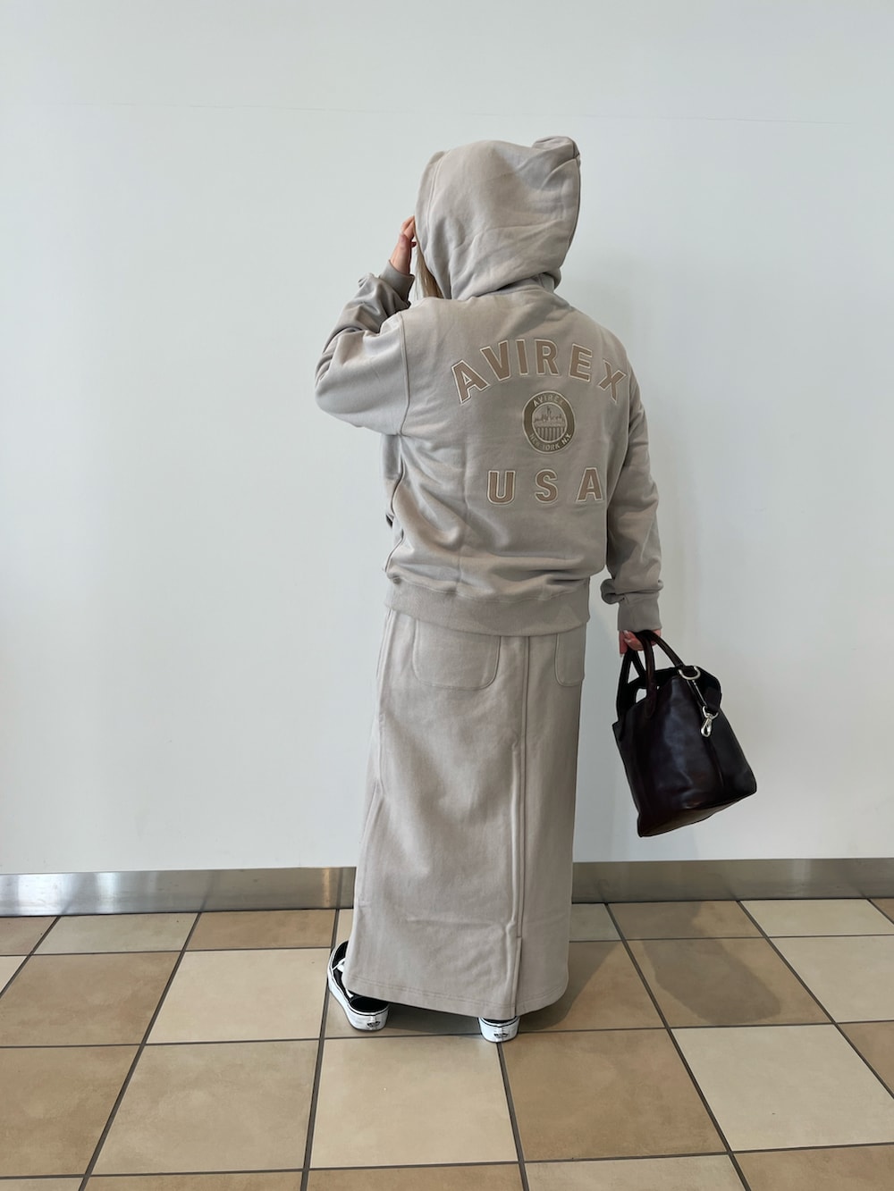 ベージュ系のパーカー、ベージュ系のスカート、ブラウン系のトートバッグを着用したレディースの秋コーディネートの3枚目の写真