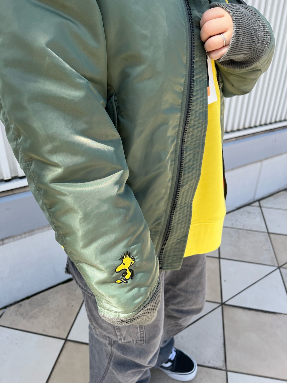 グリーン系のMA-1、イエロー系のスウェット、ブラック系のデニムパンツを着用したレディースの秋コーディネートの3枚目の写真