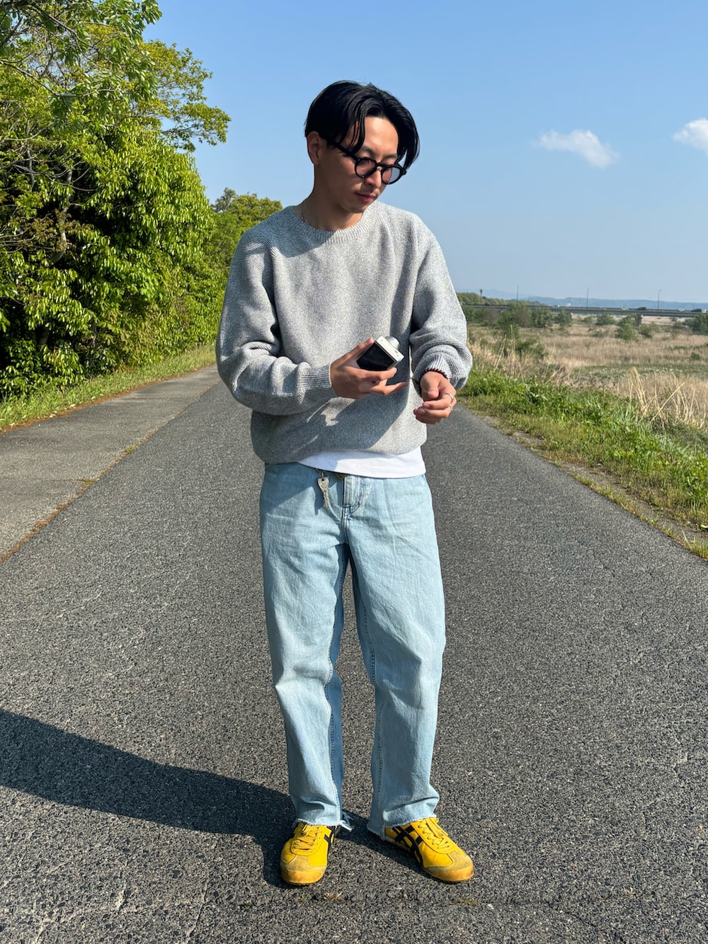 ブルー系のデニムパンツ、イエロー系のスニーカー、グレー系のニット/セーターを着用したメンズの春コーディネートの2枚目の写真