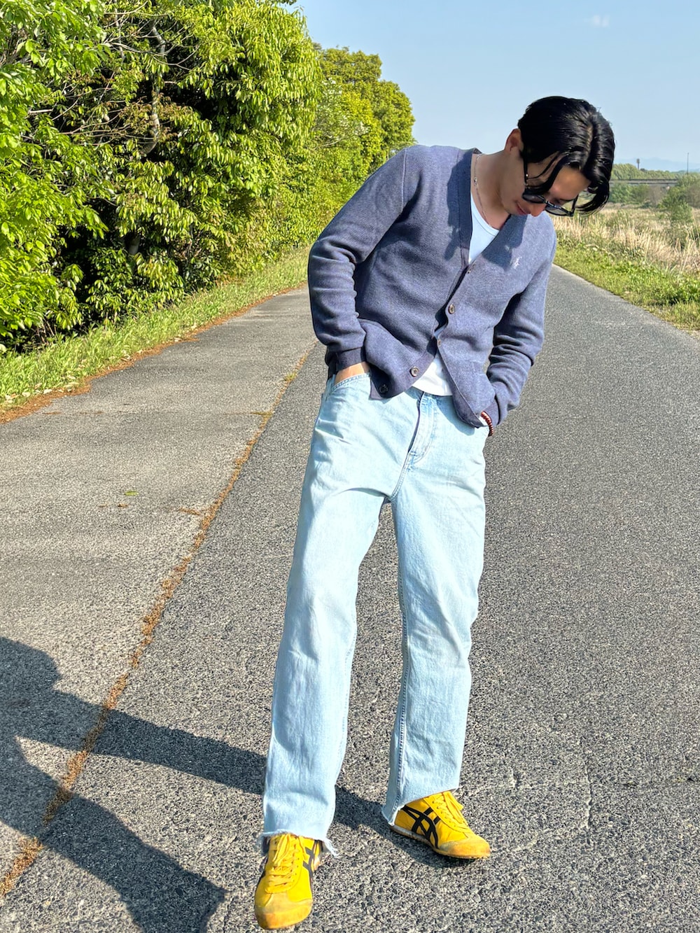 ブルー系のデニムパンツ、イエロー系のスニーカー、ホワイト系のタンクトップを着用したメンズの春コーディネートの2枚目の写真