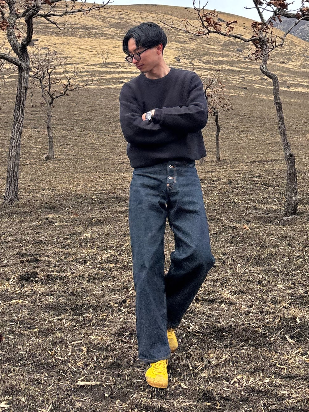 ブラック系のニット/セーター、ブルー系のデニムパンツ、イエロー系のスニーカーを着用したメンズの春コーディネートの2枚目の写真