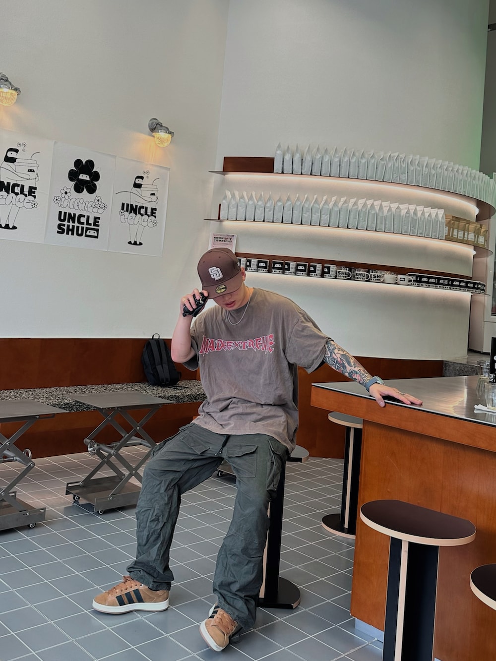 ブラウン系のTシャツ/カットソー、グリーン系のチノパンツ、グレー系のスニーカーを着用したメンズの春コーディネートの2枚目の写真