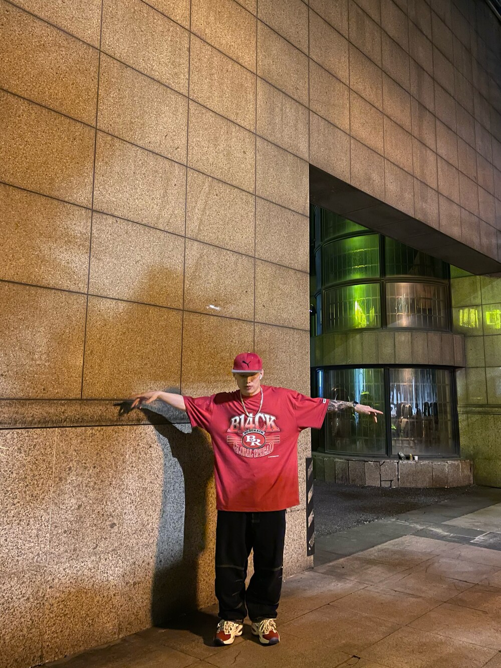 レッド系のスニーカー、ブルー系のデニムパンツ、レッド系のTシャツ/カットソーを着用したメンズの春コーディネートの2枚目の写真