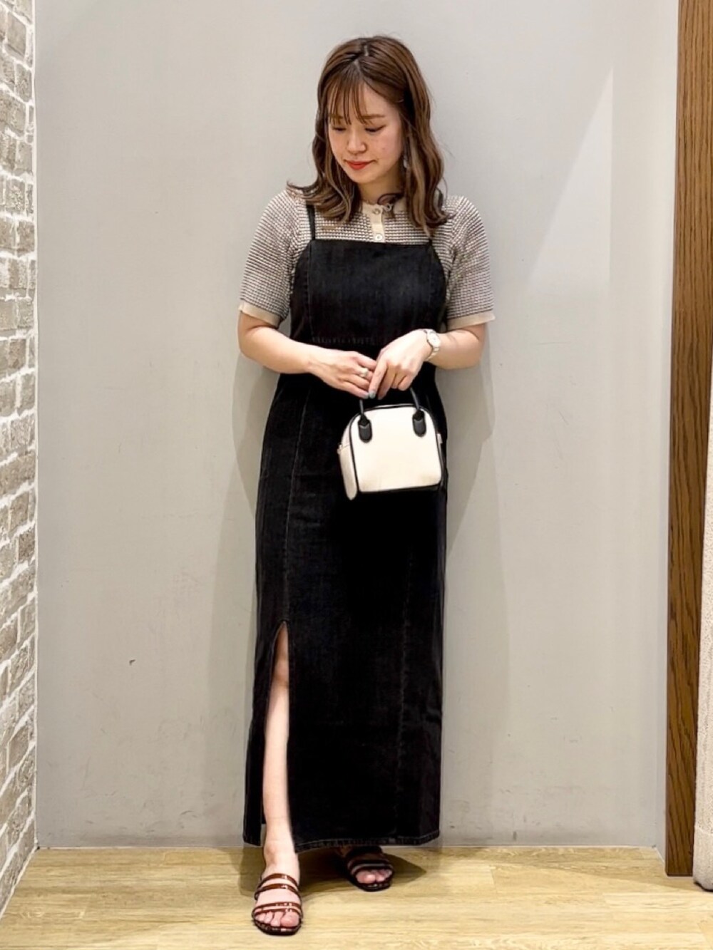 ベージュ系のトートバッグ、ベージュ系のカーディガン/ボレロ、ブラック系のワンピースを着用したレディースの春コーディネートの2枚目の写真