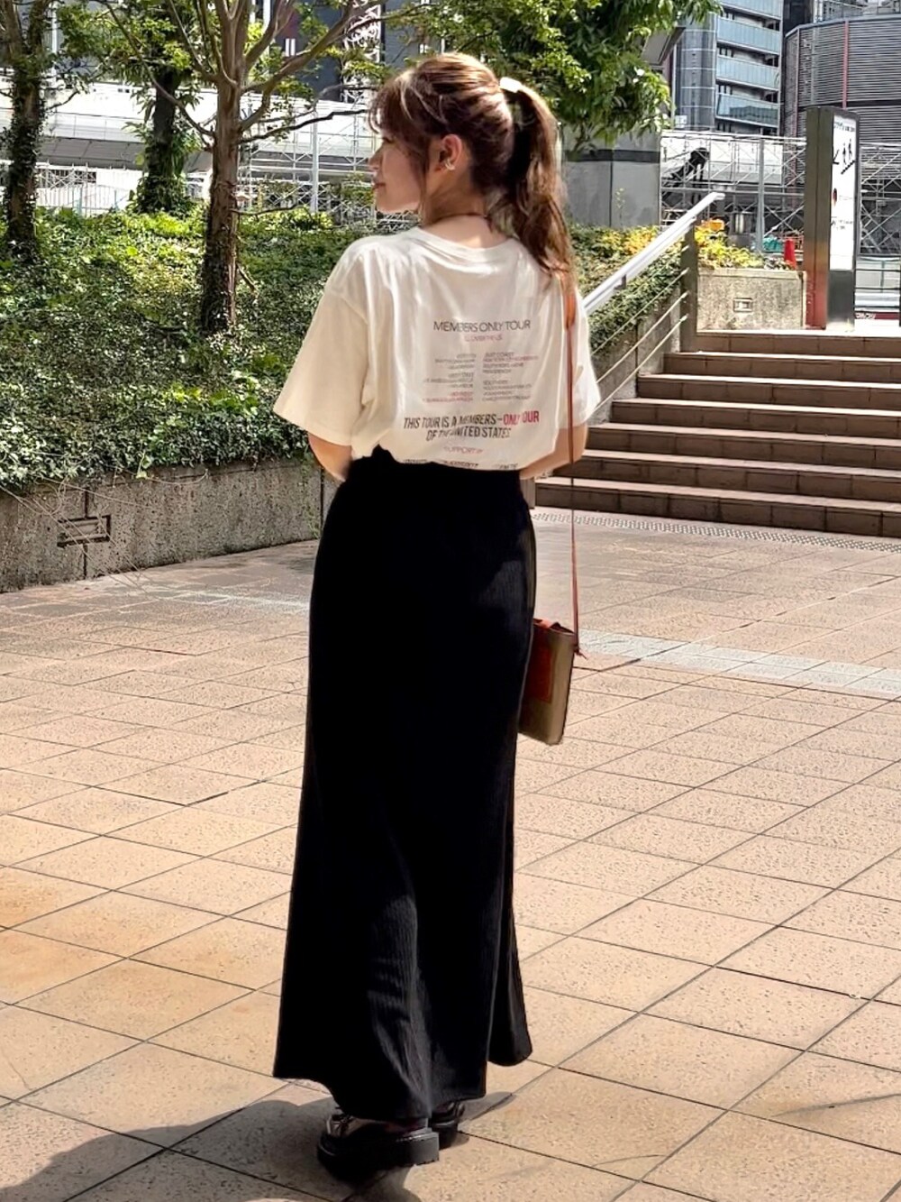 ホワイト系のTシャツ/カットソー、ブラック系のスカート、ブラウン系のローファーを着用したレディースの夏コーディネートの2枚目の写真