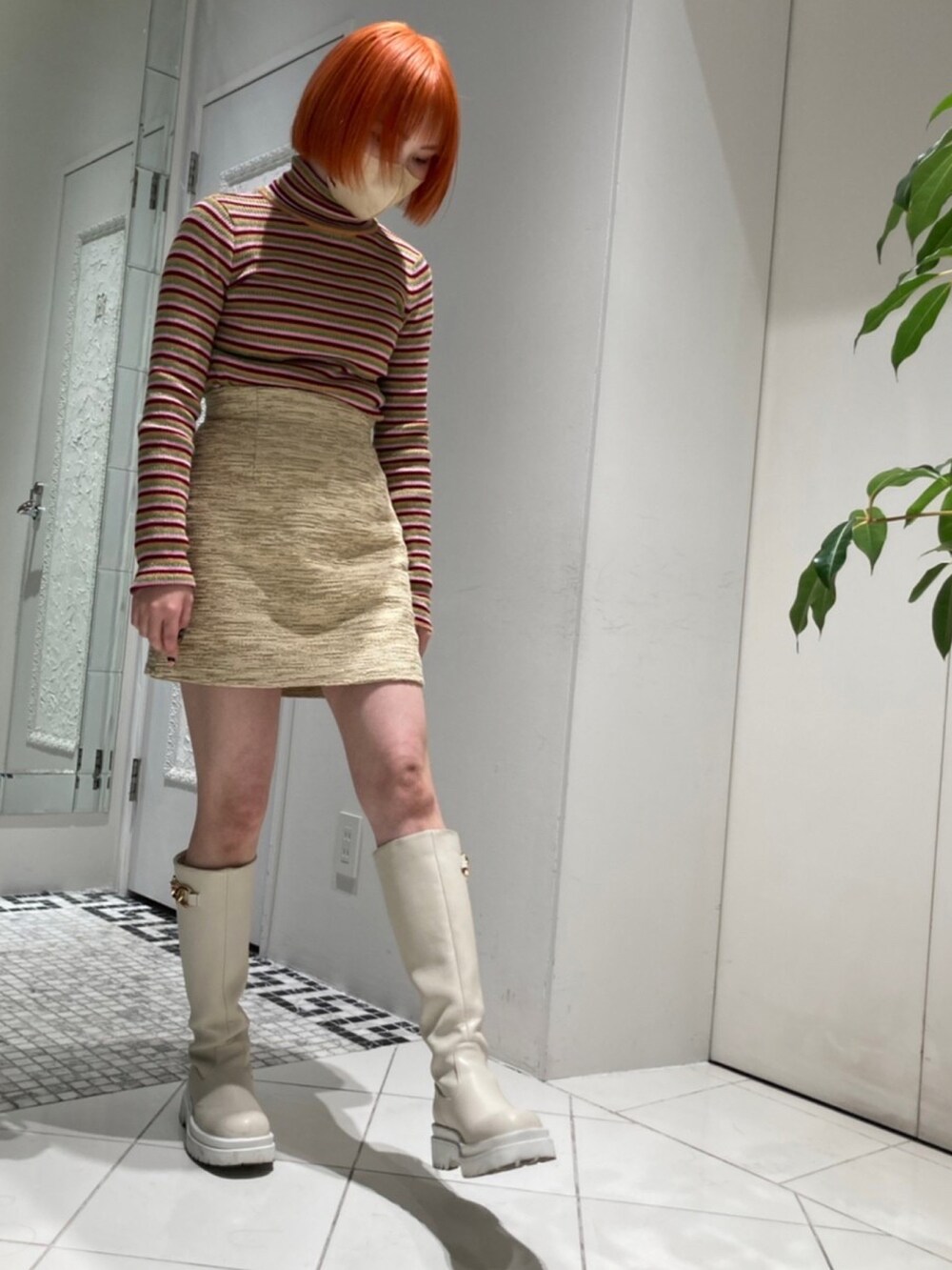 ホワイト系のブーツ、ベージュ系のスカート、グリーン系のニット/セーターを着用したレディースの冬コーディネートの2枚目の写真