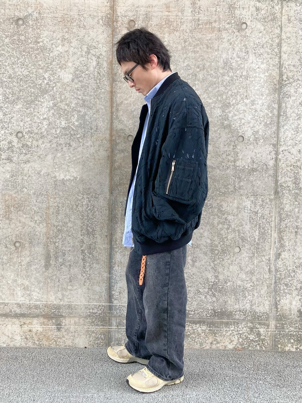 ブラック系のデニムパンツ、ベージュ系のスニーカー、ブラック系のブルゾンを着用したメンズの春コーディネートの2枚目の写真