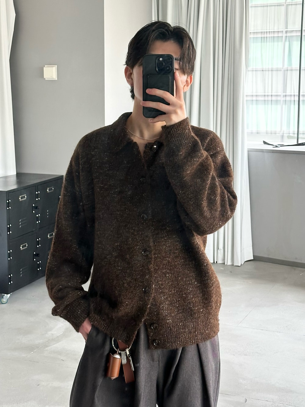 ブラウン系のニット/セーター、グレー系のスラックス、グレー系のスニーカーを着用したメンズの冬コーディネートの2枚目の写真