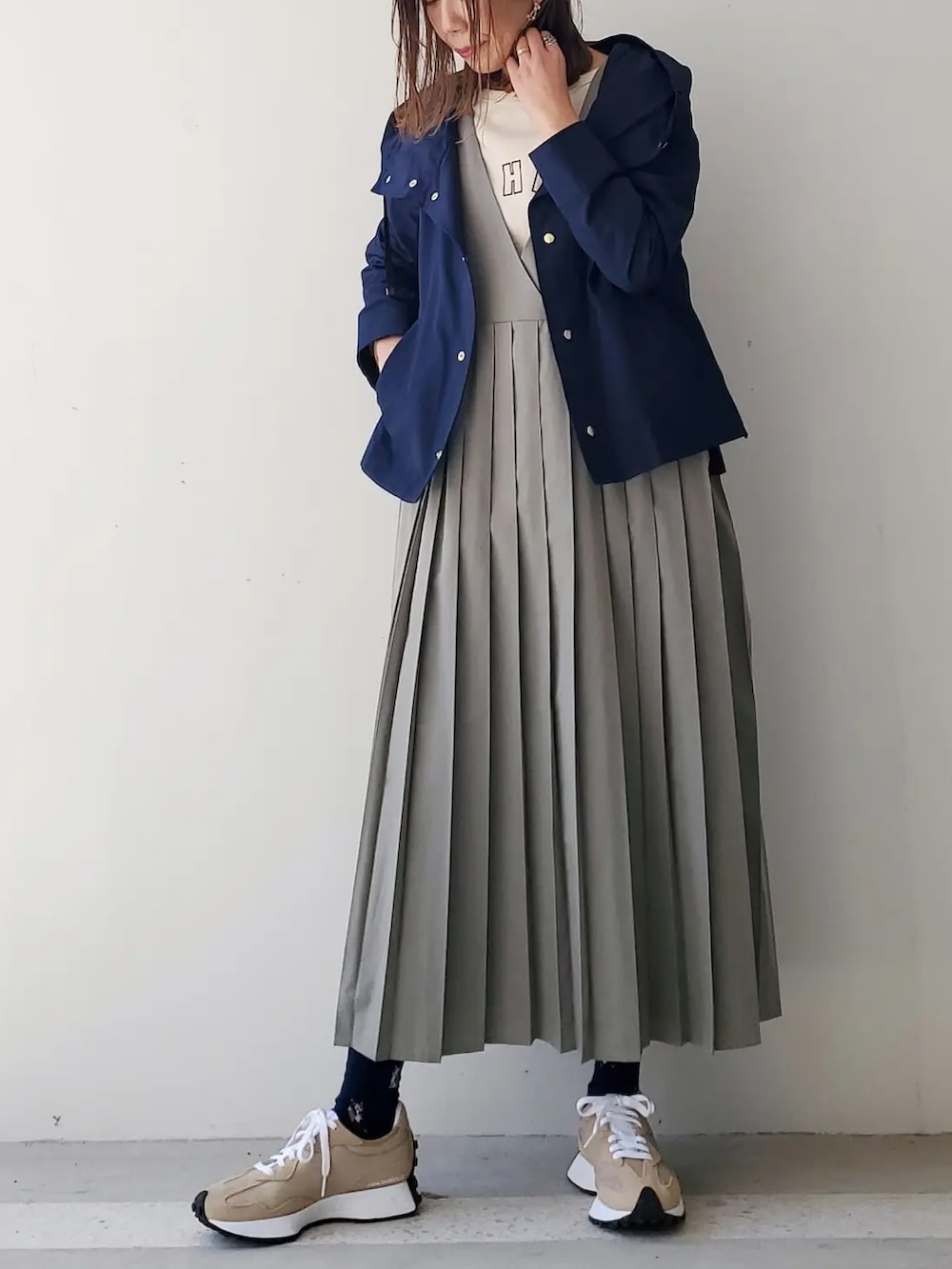 ホワイト系のTシャツ/カットソー、グリーン系のジャンパースカート、ベージュ系のスニーカーを着用したレディースの春コーディネートの2枚目の写真
