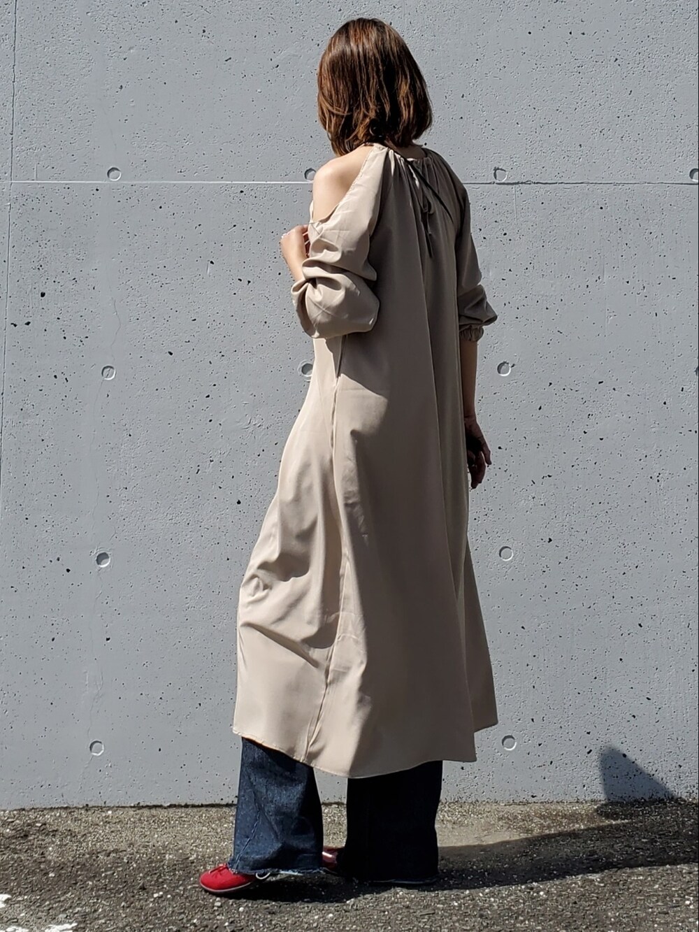 ベージュ系のワンピース、ブルー系のデニムパンツ、レッド系のバレエシューズを着用したレディースの春コーディネートの2枚目の写真