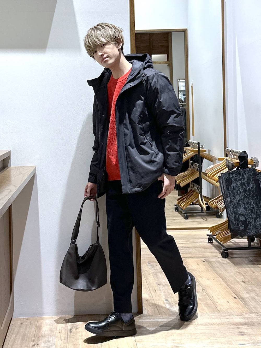 ブラック系のダウンジャケット/コート、ブルー系のスラックス、レッド系のニット/セーターを着用したメンズの冬コーディネートの2枚目の写真