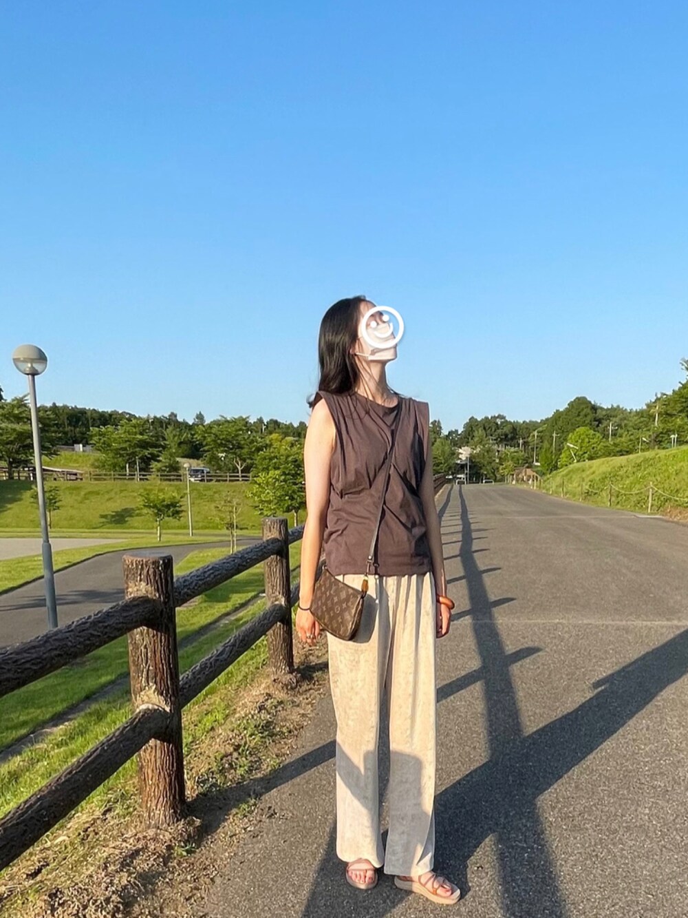 グレー系のタンクトップ、ベージュ系のサンダル、ホワイト系のその他パンツを着用したレディースの春コーディネートの2枚目の写真
