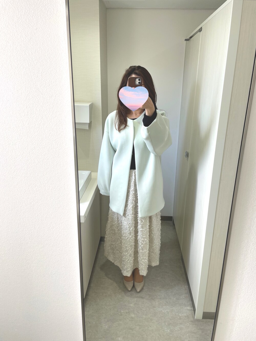 グリーン系のノーカラーコートを着用したレディースの春コーディネートの2枚目の写真