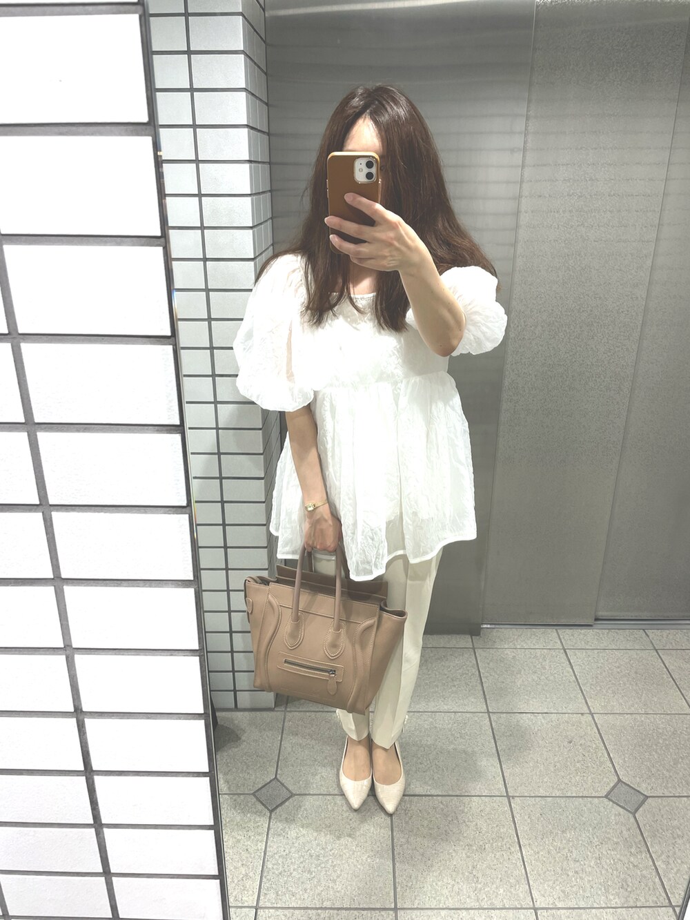 ホワイト系のパンプス、ベージュ系のハンドバッグ、ホワイト系のTシャツ/カットソーを着用したレディースの夏コーディネートの2枚目の写真