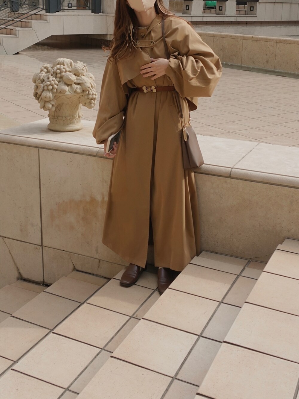 ベージュ系のトレンチコート、ブラウン系のショルダーバッグ、ブラウン系のベルトを着用したレディースの春コーディネートの4枚目の写真
