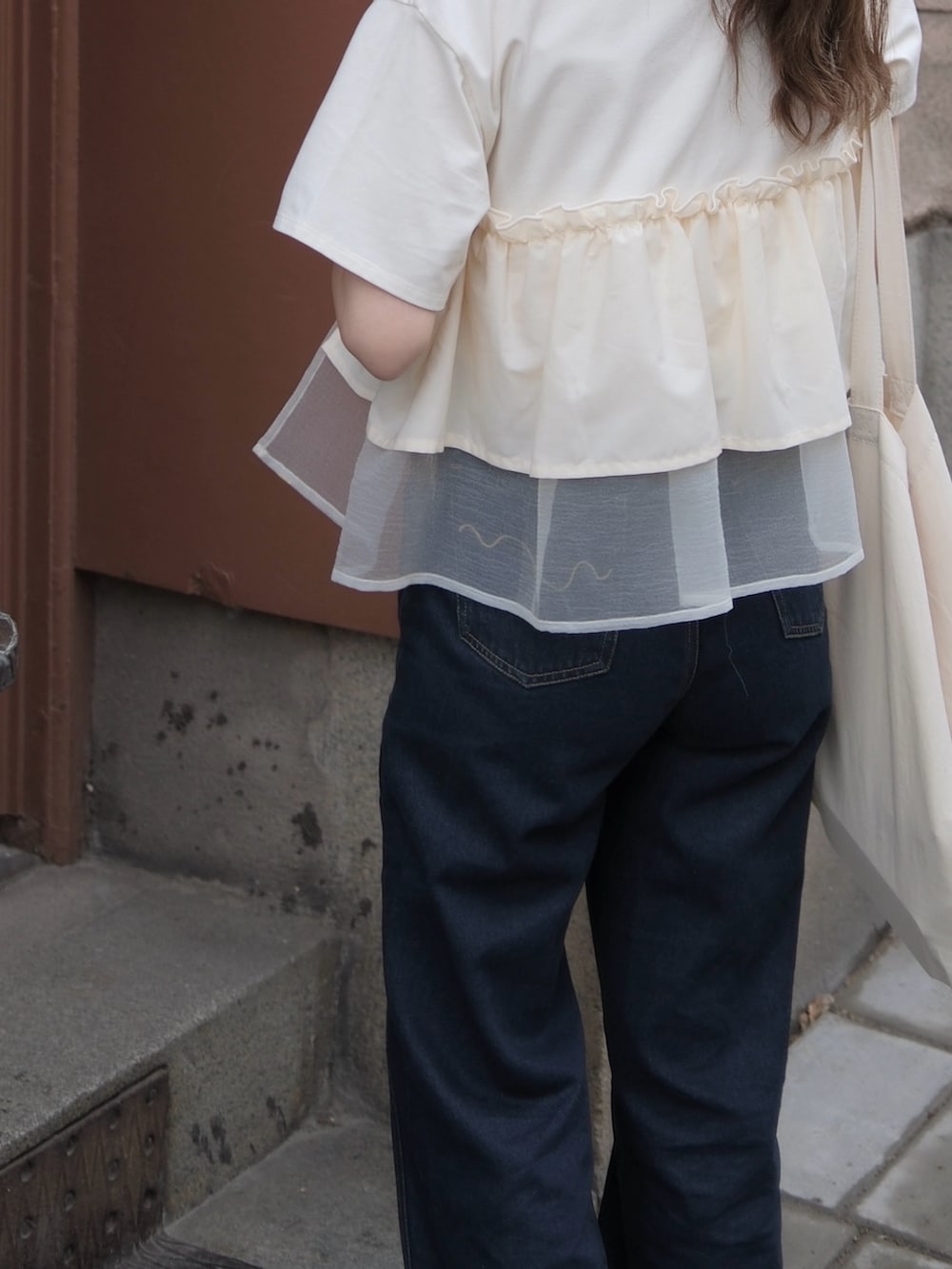 ベージュ系のTシャツ/カットソー、ブルー系のデニムパンツを着用したレディースの秋コーディネートの2枚目の写真