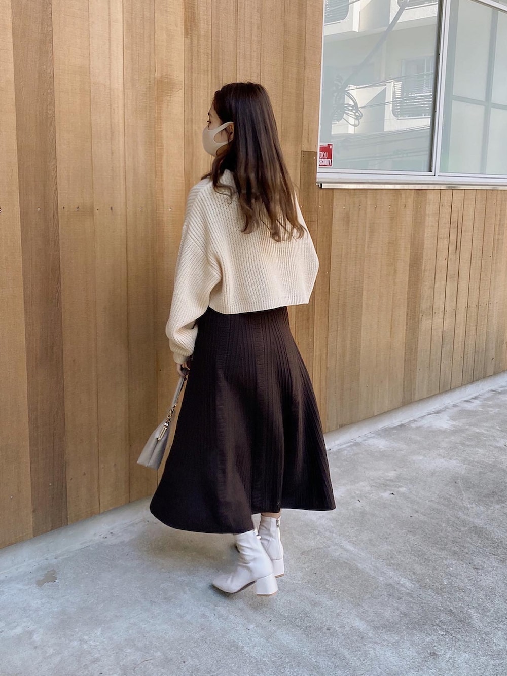 ベージュ系のショルダーバッグ、ホワイト系のカーディガン/ボレロ、ブラック系のTシャツ/カットソーを着用したレディースの冬コーディネートの4枚目の写真