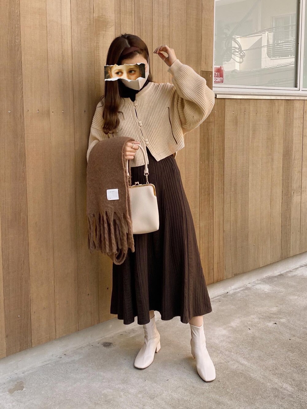 ベージュ系のショルダーバッグ、ホワイト系のカーディガン/ボレロ、ブラック系のTシャツ/カットソーを着用したレディースの冬コーディネートの2枚目の写真