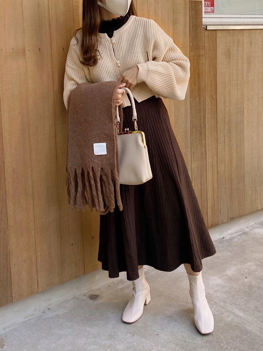 ベージュ系のショルダーバッグ、ホワイト系のカーディガン/ボレロ、ブラック系のTシャツ/カットソーを着用したレディースの冬コーディネートの3枚目の写真