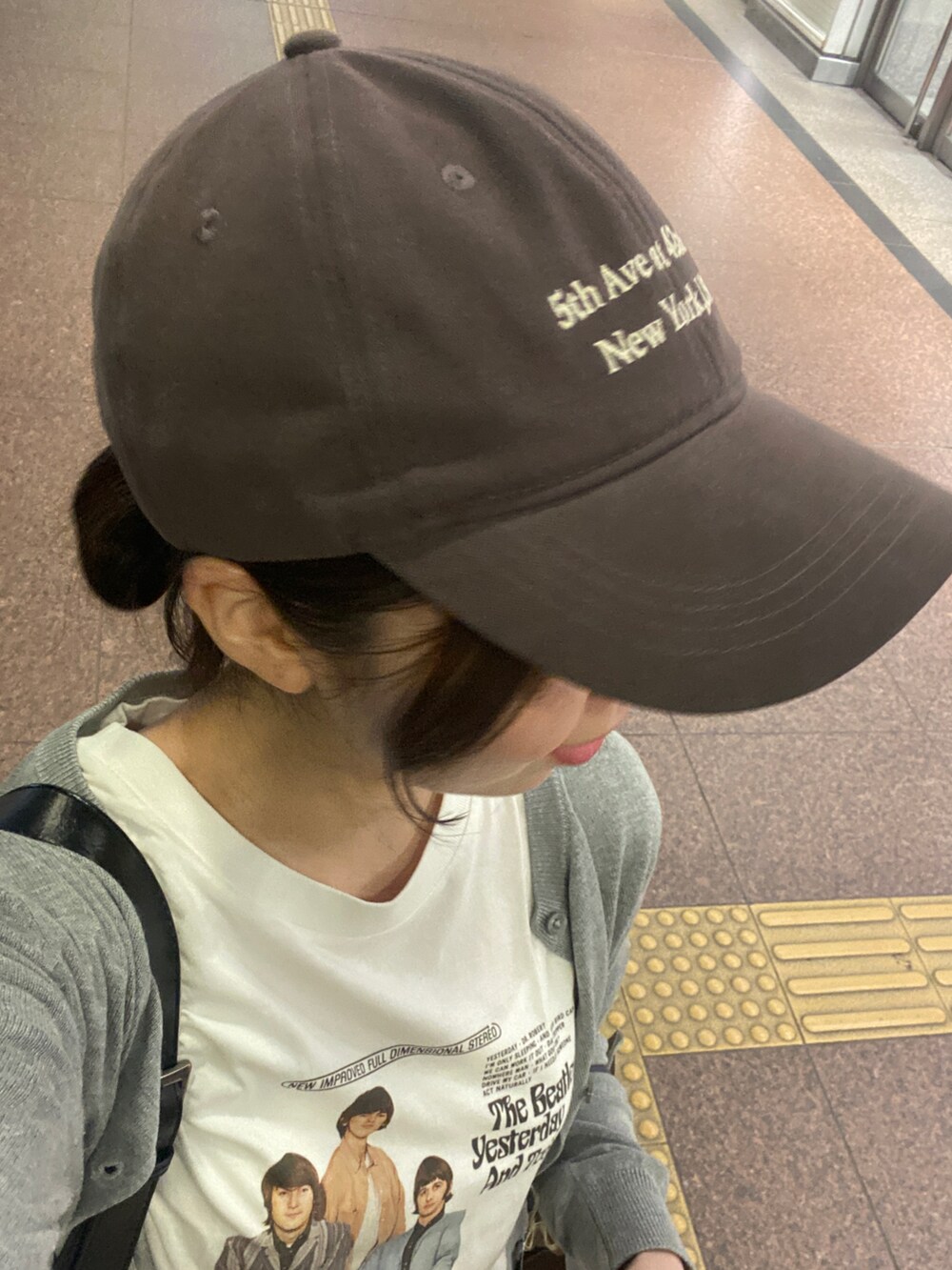 グレー系のカーディガン/ボレロ、ホワイト系のTシャツ/カットソー、ブラウン系のキャップを着用したレディースの夏コーディネートの2枚目の写真