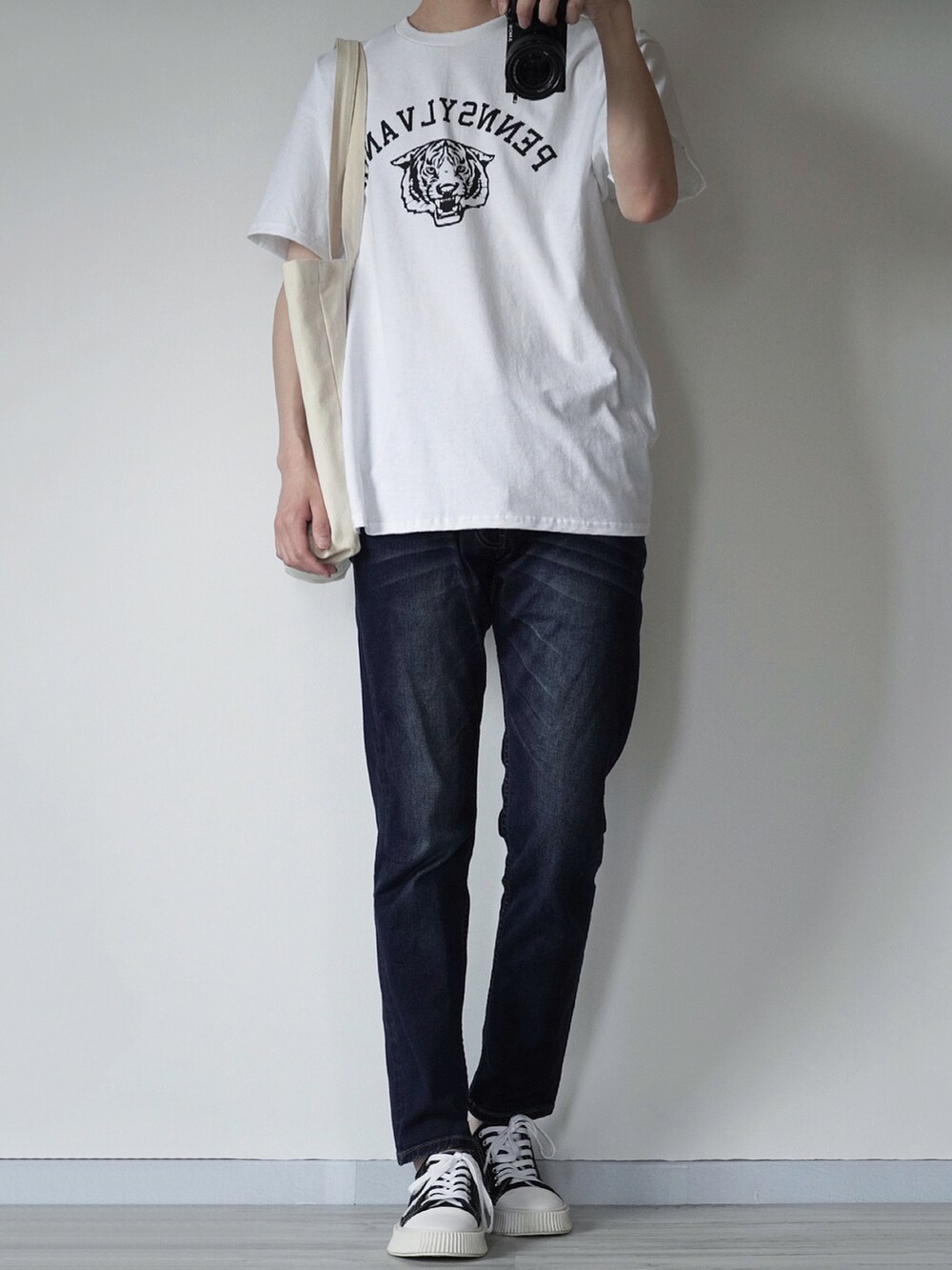 ホワイト系のTシャツ/カットソー、ブルー系のデニムパンツ、ブラック系のスニーカーを着用したメンズの春コーディネートの2枚目の写真