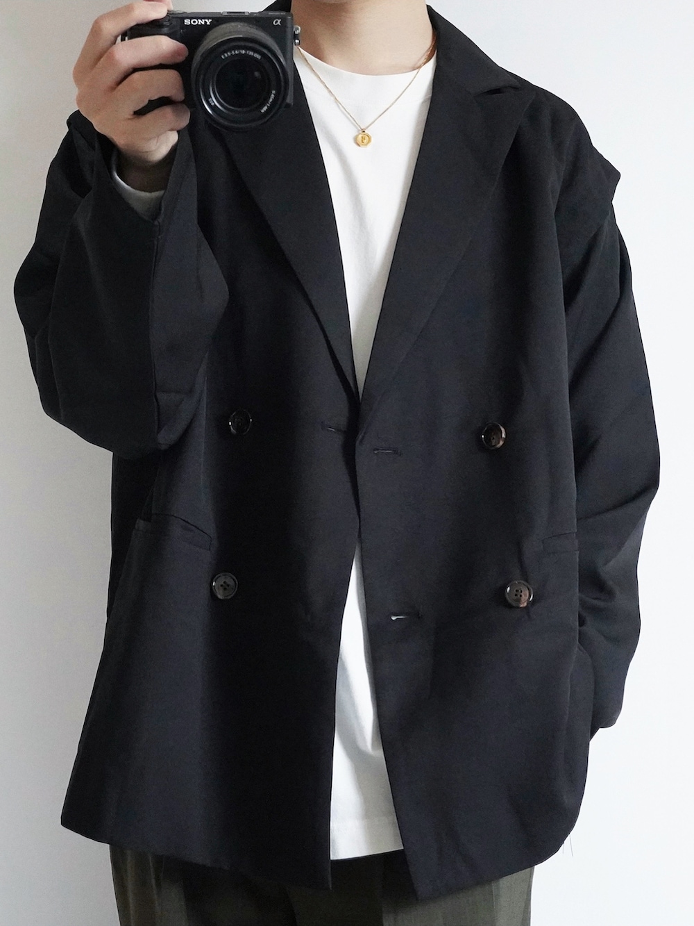 ブラック系のテーラードジャケット、ホワイト系のTシャツ/カットソー、グリーン系のスラックスを着用したメンズの秋コーディネートの2枚目の写真