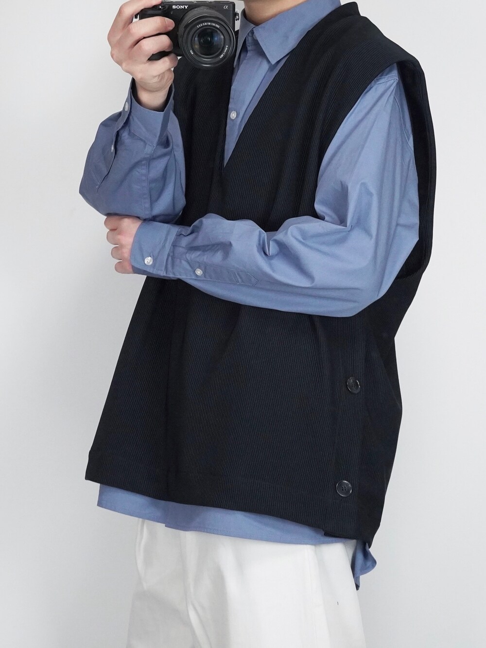 ホワイト系のデニムパンツ、ブラック系のドレスシューズ、ブラック系のベストを着用したメンズの冬コーディネートの2枚目の写真