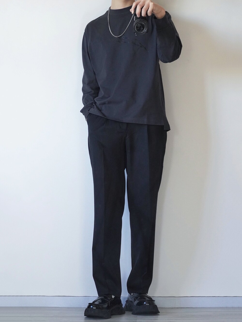 グレー系のブルゾン、グレー系のTシャツ/カットソー、ブラック系のスラックスを着用したメンズの冬コーディネートの2枚目の写真