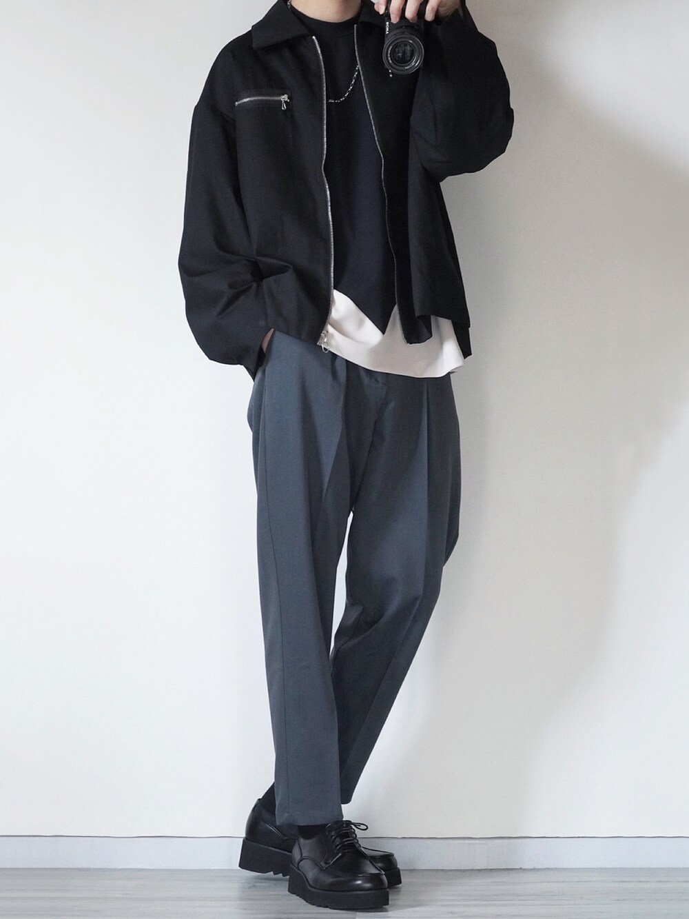 ブルー系のスラックス、ブラック系のTシャツ/カットソー、ブラック系のドレスシューズを着用したメンズの冬コーディネートの2枚目の写真