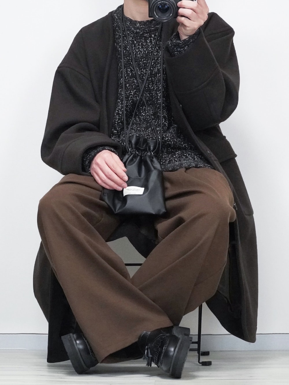 ブラウン系のその他パンツ、ブラウン系のノーカラーコート、ブラック系のニット/セーターを着用したメンズの冬コーディネートの2枚目の写真