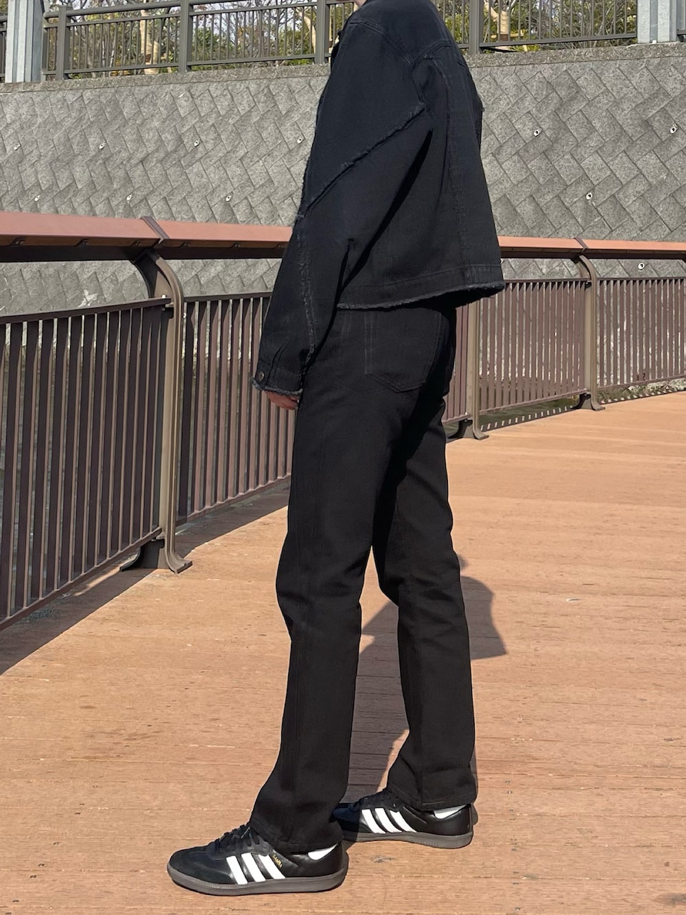 ブラック系のデニムジャケット、ブラック系のデニムパンツ、ブラック系のスニーカーを着用したメンズの春コーディネートの3枚目の写真