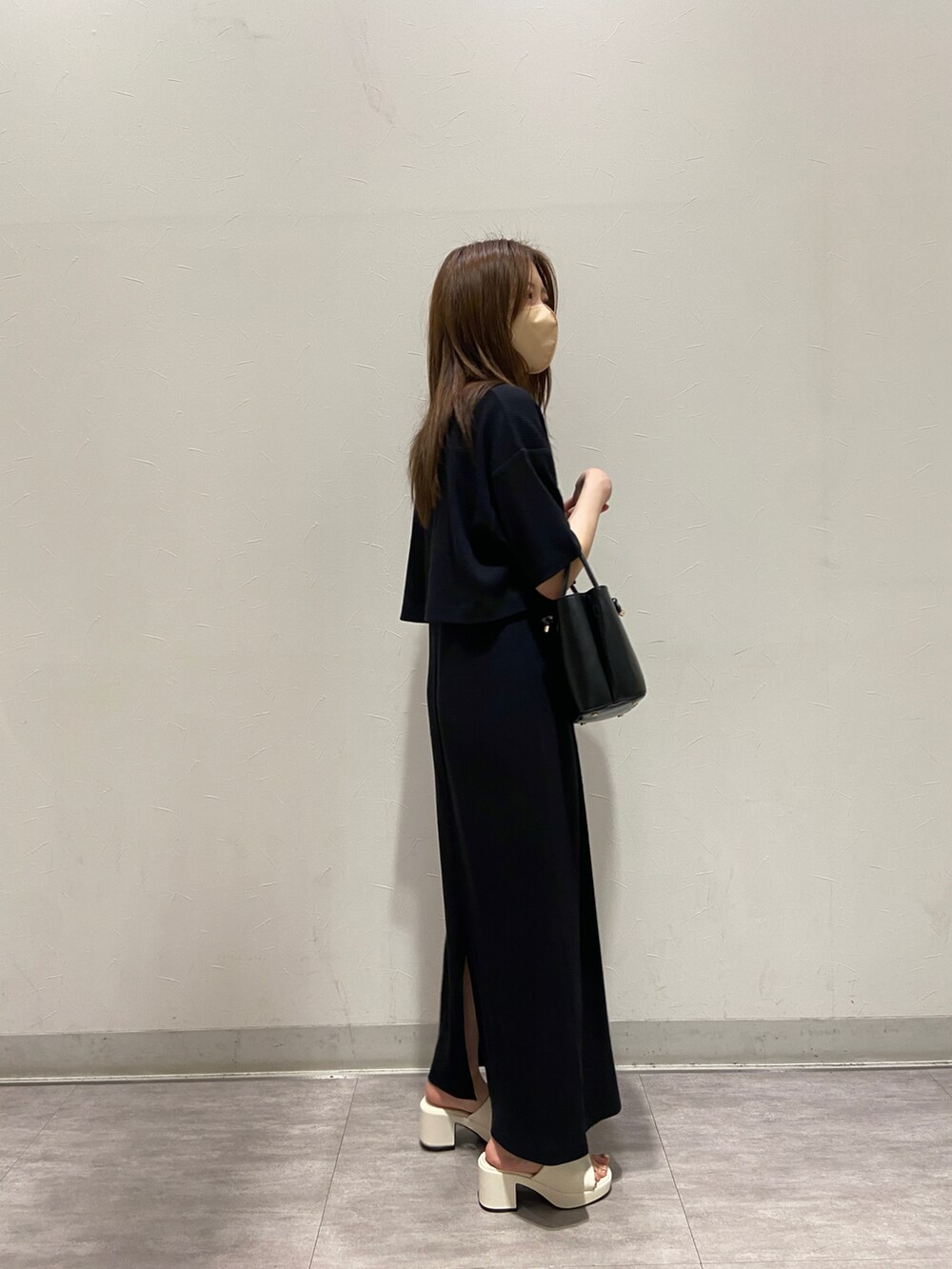 ブラック系のバッグ、ホワイト系のサンダル、ブラック系のワンピースを着用したレディースの春コーディネートの2枚目の写真