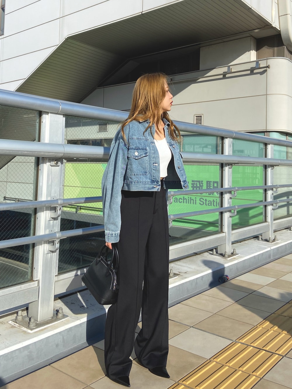 ホワイト系のタンクトップ、ブルー系のデニムジャケット、ブラック系のボストンバッグを着用したレディースの春コーディネートの2枚目の写真