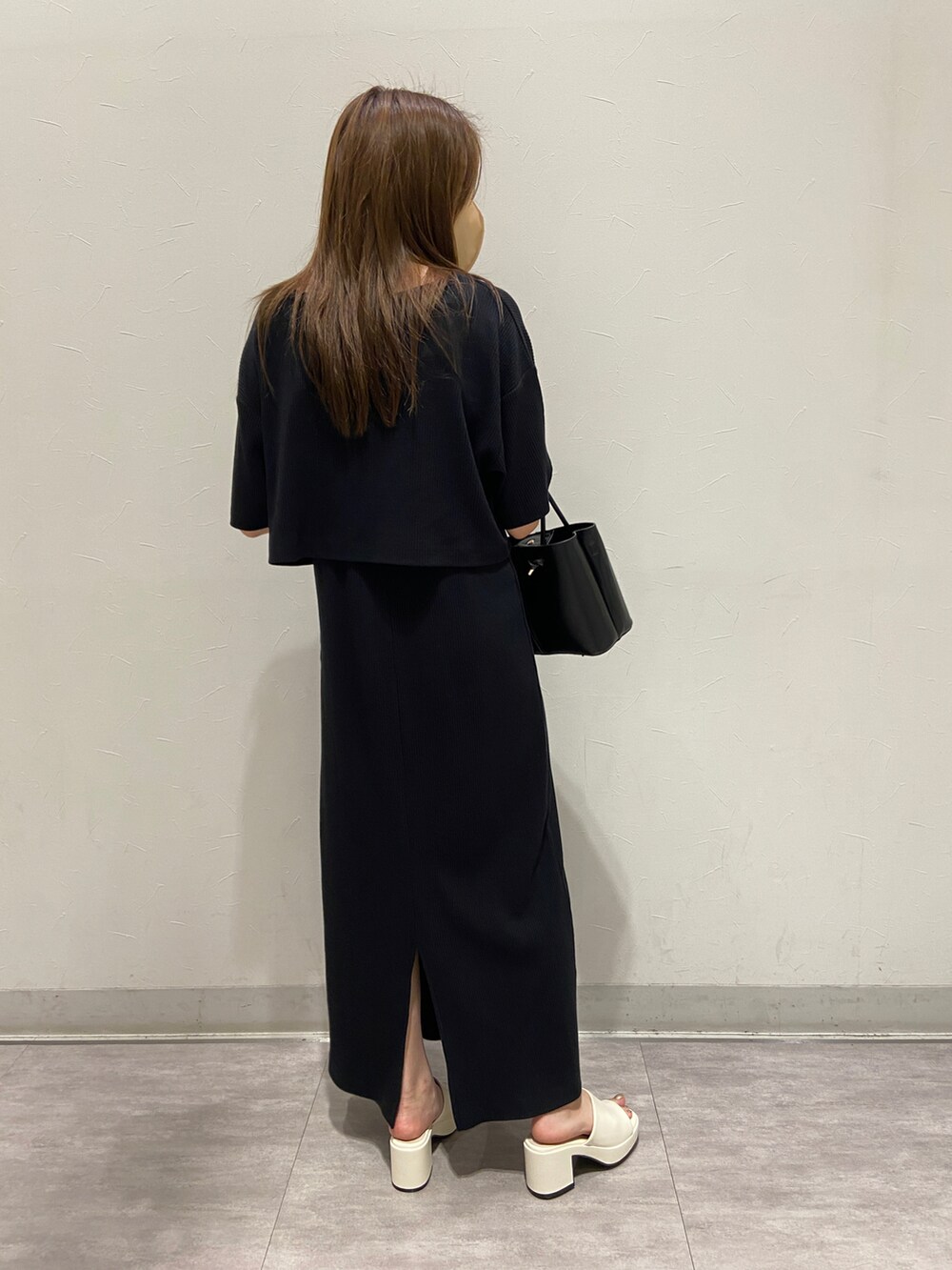 ブラック系のバッグ、ホワイト系のサンダル、ブラック系のワンピースを着用したレディースの春コーディネートの3枚目の写真