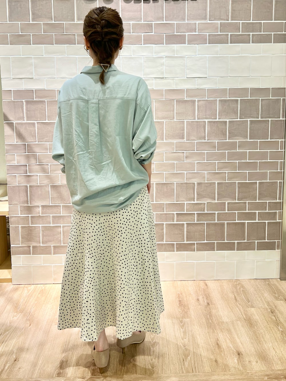 ホワイト系のスカート、ベージュ系のパンプス、グリーン系のシャツ/ブラウスを着用したレディースの夏コーディネートの2枚目の写真