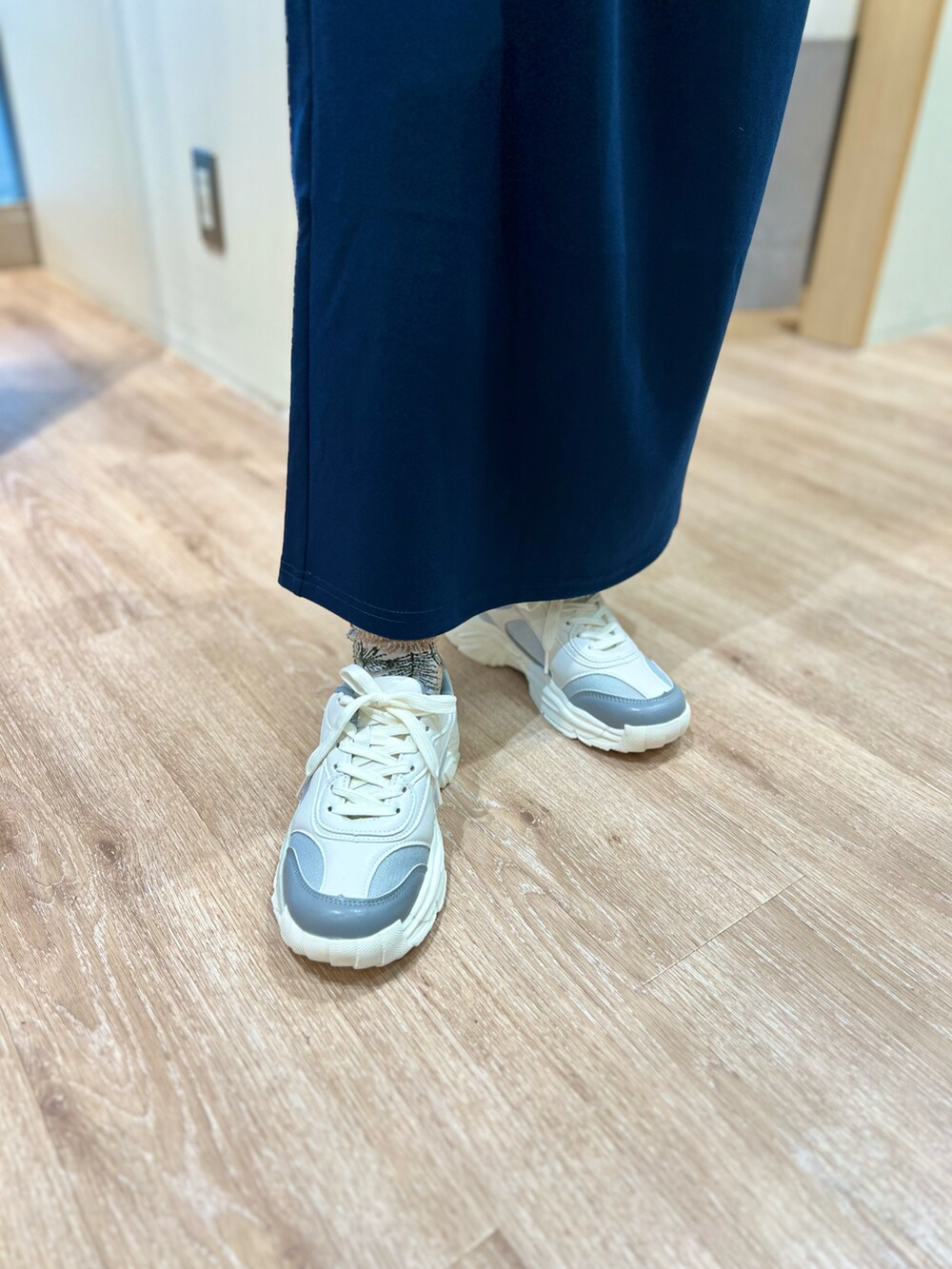 グレー系のTシャツ/カットソー、ブルー系のスカート、グレー系のスニーカーを着用したレディースの秋コーディネートの4枚目の写真