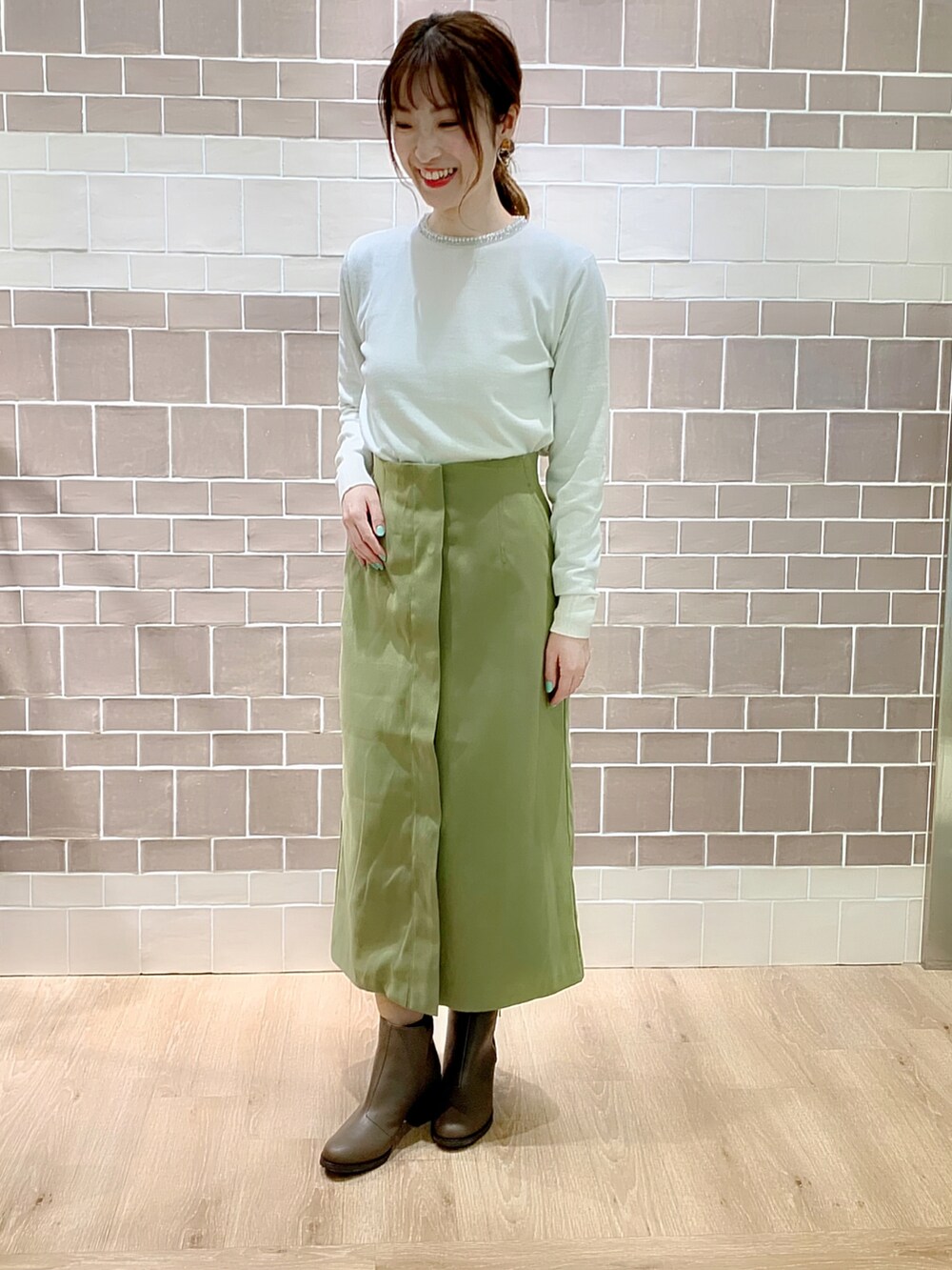 グリーン系のスカート、ベージュ系のノーカラーコート、ベージュ系のブーツを着用したレディースの冬コーディネートの4枚目の写真