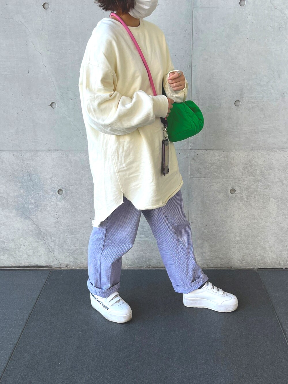 グリーン系のバッグ、ホワイト系のトップス、ホワイト系のスニーカーを着用したレディースの秋コーディネートの2枚目の写真