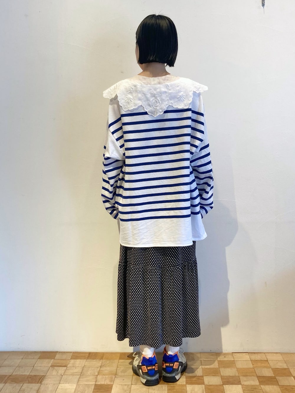 ブラック系のスカート、ブルー系のTシャツ/カットソー、ブルー系のスニーカーを着用したレディースの秋コーディネートの3枚目の写真