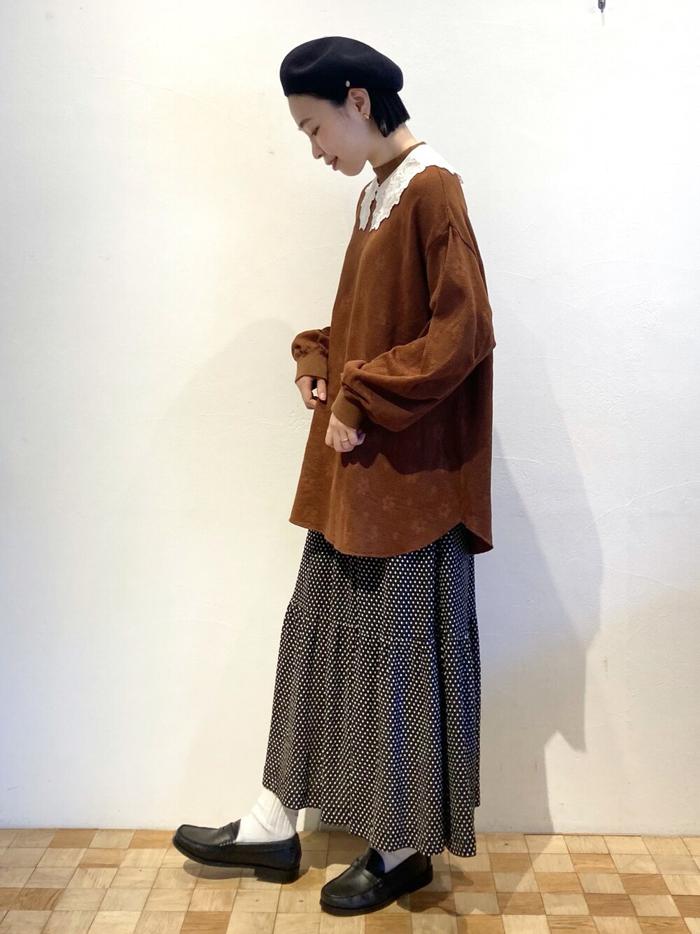 ブラック系のスカート、ブラウン系のTシャツ/カットソー、ホワイト系の付け襟を着用したレディースの秋コーディネートの2枚目の写真