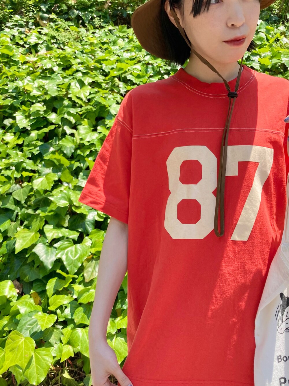 オレンジ系のTシャツ/カットソー、ブルー系のデニムパンツを着用したレディースの春コーディネートの4枚目の写真