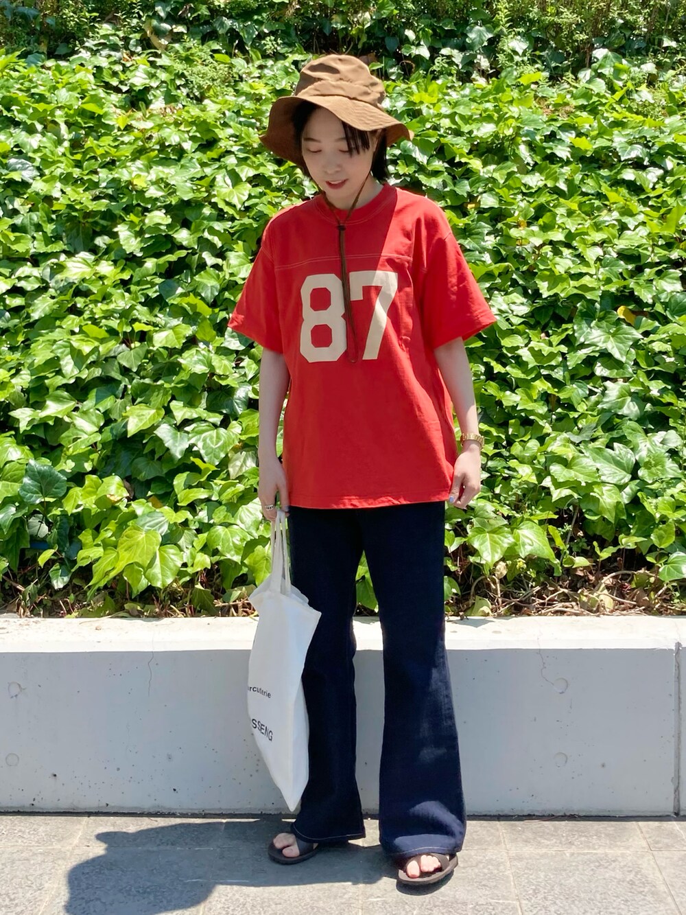 オレンジ系のTシャツ/カットソー、ブルー系のデニムパンツを着用したレディースの春コーディネートの3枚目の写真