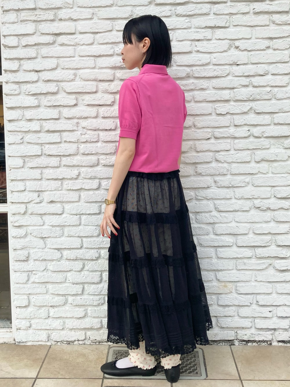 ピンク系のポロシャツ、ブラック系のスカート、ホワイト系のレギンス/スパッツを着用したレディースの春コーディネートの2枚目の写真