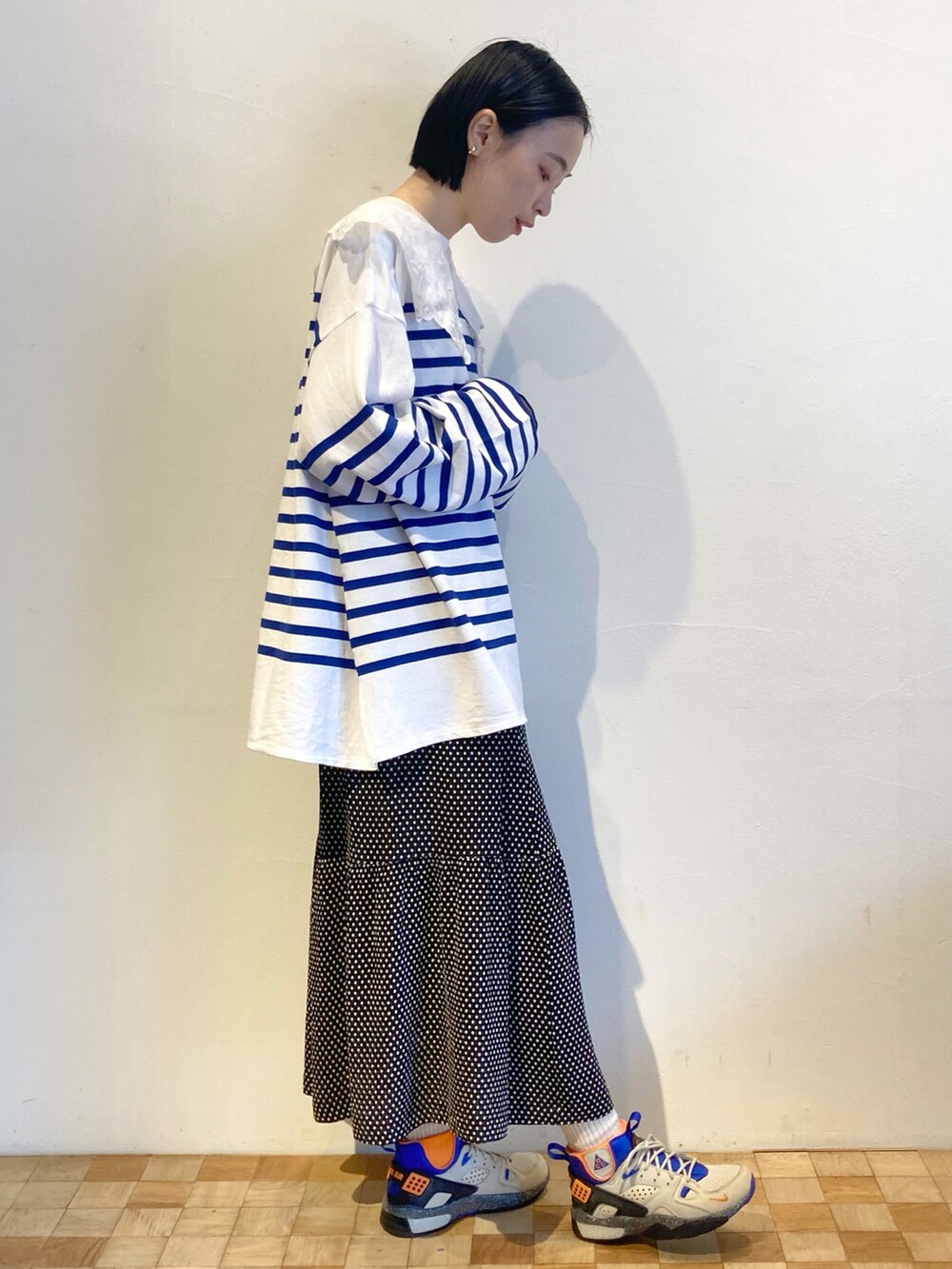 ブラック系のスカート、ブルー系のTシャツ/カットソー、ブルー系のスニーカーを着用したレディースの秋コーディネートの2枚目の写真