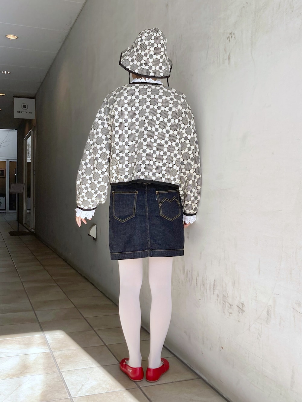 ブルー系のデニムスカート、ブラック系のカーディガン/ボレロ、ホワイト系のシャツ/ブラウスを着用したレディースの冬コーディネートの2枚目の写真